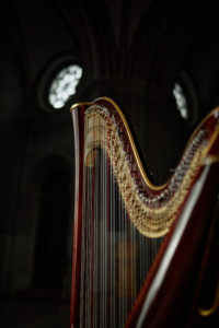 Cropped shot of antique wooden harp with elegant curved frame captured in low key light inside church, copy space